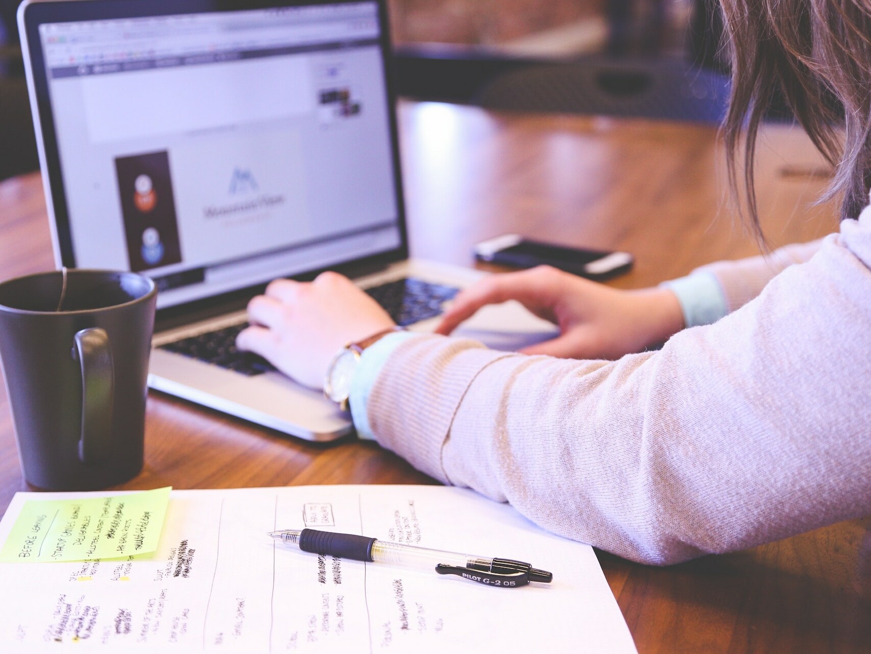 Woman typing on a computer with papers next to her