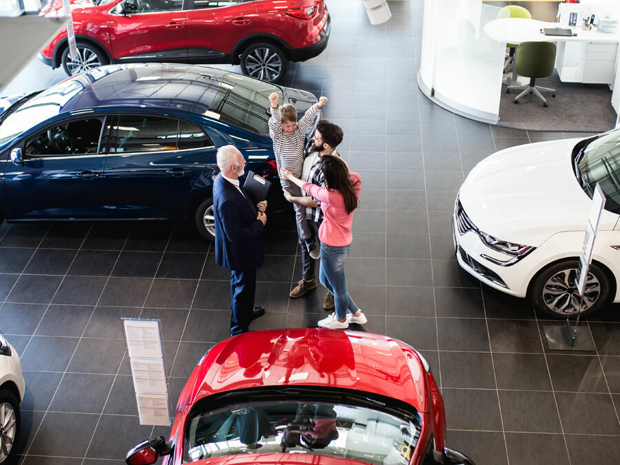 Car dealership floor with happy customers and salesmen