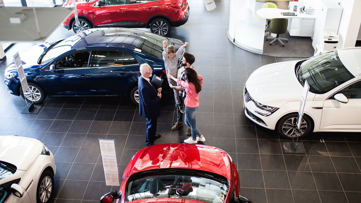 Car dealership floor with happy customers and salesmen